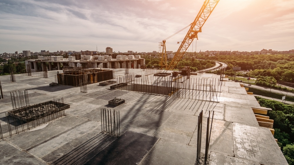 Roof of construction site of new multi-storey residential building, industrial construction crane and other industry equipment.